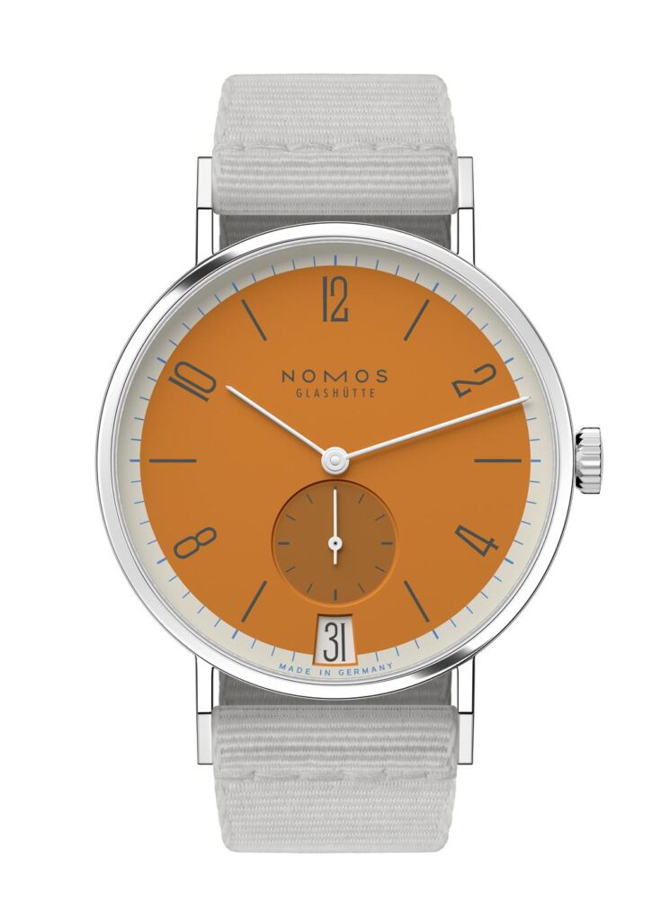 NOMOS Glashütte watch features an orange dial, stainless steel case, and grey fabric strap.