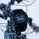 Black Casio G-Shock watch against an abstract crystalline background with geometric shapes and metallic accents.