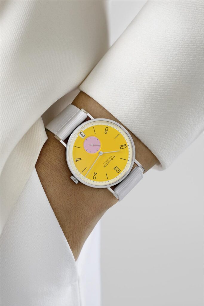 Vibrant yellow watch on a wrist, featuring stylish pink sub-dial and white strap.