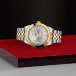 Luxurious silver and gold wristwatch displayed on a striking black and red background.
