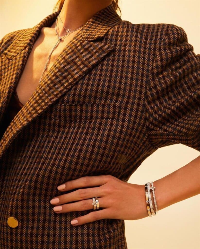 Stylish person in oversized plaid blazer with layered necklaces and elegant bracelets.