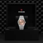 Luxurious Tudor watch in elegant box featuring rose gold dial and polished stainless steel bracelet.