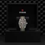 Elegant Tudor watch in stylish display box, featuring a khaki strap and sophisticated gray dial.