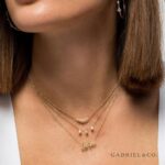 Fashionable woman wearing layered gold necklaces, showcasing elegance and sophistication in jewelry styling.