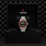 Elegant Tudor watch in a black box with a striking black dial and red bezel.
