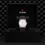 Tudor watch in luxury black box with polished steel case and brown leather strap.