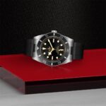 Elegant stainless steel watch on a bold red surface, showcasing timeless design and functionality.
