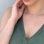 Woman in olive green top with silver jewelry, showcasing minimalist style and elegance.