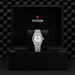 Luxurious Tudor watch in elegant box with polished stainless steel and shimmering mother-of-pearl dial.