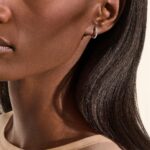 Elegant woman with smooth skin and subtle hoop earring, showcasing modern beauty and sophistication.