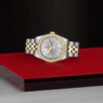 Luxurious two-tone wristwatch on red platform, featuring gold accents and diamond bezel.