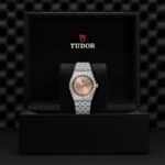 Elegant Tudor watch in polished stainless steel, showcased in a luxurious black box.