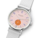 NOMOS Glashütte modern wristwatch with minimalist design, pink dial, and chic white strap.