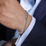 Stylish silver bracelet on well-groomed hand in tailored suit adds refined masculinity.