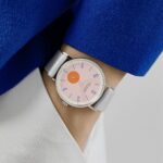 Stylish pink dial watch paired with chic outfit, showcasing modern fashion and elegance.