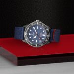 Tudor dive watch with blue dial, stainless steel case, and vibrant textile strap.