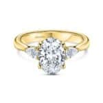 Elegant engagement ring with oval diamond and pear-shaped accents in polished yellow gold.