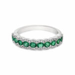 Elegant silver ring with emeralds and diamonds, showcasing luxury and sophistication.