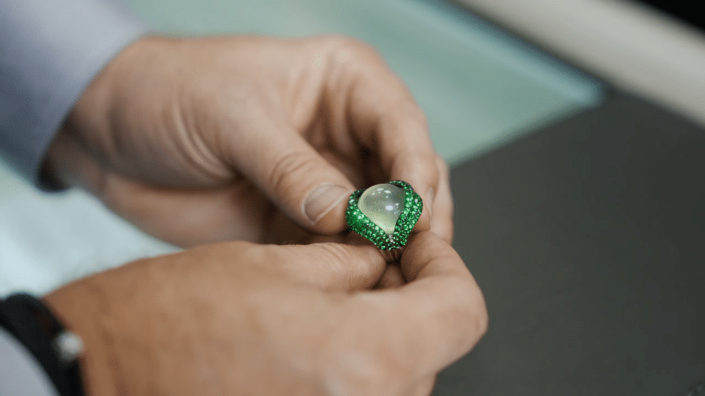 Exquisite ring with opalescent gemstone and emerald accents, showcasing luxury and craftsmanship.