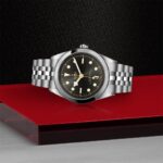 Elegant Tudor watch with a black dial and gold accents on a sleek background.