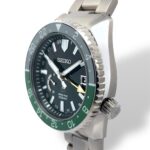 Seiko Spring Drive watch featuring a black dial, green bezel, and stylish stainless steel bracelet.