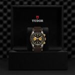 Luxurious Tudor chronograph watch in a sleek display box with a black dial and leather strap.