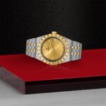 Luxurious gold watch with diamond markers on a red background, showcasing elegance and craftsmanship.