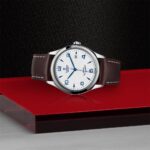 Stylish stainless steel wristwatch on red background with leather strap and minimalistic design.