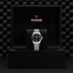 Luxurious Tudor watch on plush cushion in black box, showcasing elegance and craftsmanship.