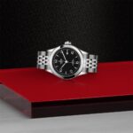 Stylish stainless steel wristwatch on vibrant red surface, showcasing elegance and sophistication.