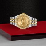 Luxurious gold and diamond watch with elegant two-tone bracelet on a striking backdrop.