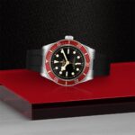 Sophisticated dive watch featuring a stainless steel case and striking red bezel on a glossy surface.