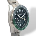 Sophisticated Seiko GMT watch features a black dial, green bezel, and stainless steel design.