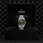 Elegant Tudor watch displayed in luxurious black presentation box with exquisite detailing.