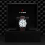 Luxury Tudor watch in elegant box, showcasing craftsmanship and style with leather strap and date function.