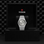 Elegant Tudor watch in a luxurious black box showcasing stainless steel design and Roman numerals.