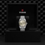 Tudor luxury watch in elegant display box with polished silver bracelet and gold dial.
