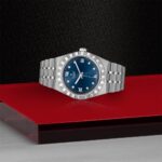 Elegant stainless steel watch with blue dial and diamond markers on a striking red surface.