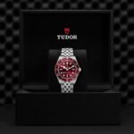 Luxurious Tudor watch with red dial displayed in an elegant black presentation box.