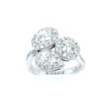 Elegant three-stone diamond ring with pear and round gemstones in a luxurious halo setting.