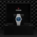 Elegant Tudor watch in luxurious black box with blue dial and stainless steel bracelet.