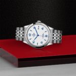Stylish Tudor watch on a red surface, showcasing luxury craftsmanship and elegant design.
