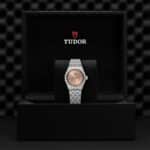Elegant Tudor watch in luxurious display box, featuring rose gold dial and stainless steel bracelet.