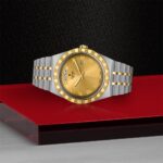 Luxurious silver and gold watch with Roman numerals, date window, and elegant design.