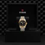 Luxurious Tudor watch in elegant box, showcasing black dial and two-tone bracelet design.
