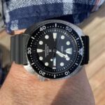 Stylish dive watch on wrist with stainless steel case and rubber strap, perfect for underwater adventures.