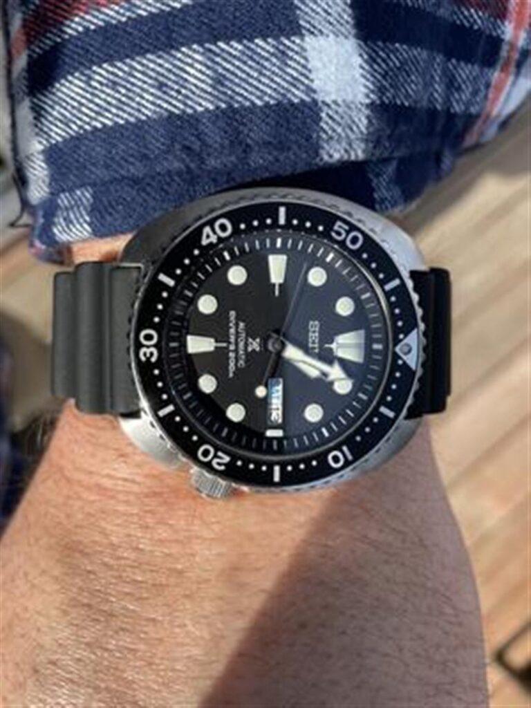 Stylish dive watch on wrist with stainless steel case and rubber strap, perfect for underwater adventures.