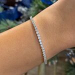 Elegant gemstone bracelet on warm skin tone, set against festive holiday backdrop.