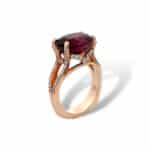 Elegant rose gold ring with a striking red gemstone and diamond accents.