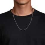 Close-up of elegant silver chain on neck with minimalist black t-shirt against a white background.